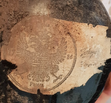 The torn sheet on the bottle, its circular impression showing a double-headed eagle legended TROIS above, PATARS below, and the year split 17 — 86 across the field