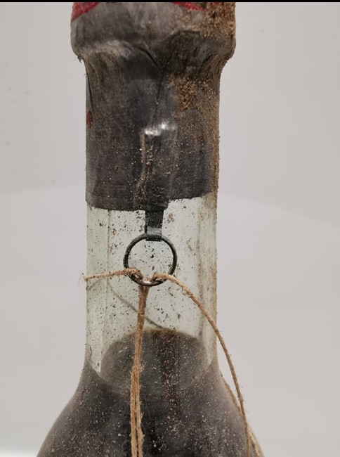 A wire ring set into the neck with cord tied through it, running under the capsule