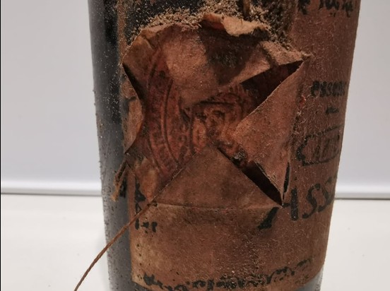 The paper over the label, broken open, with the impression of a seal beneath