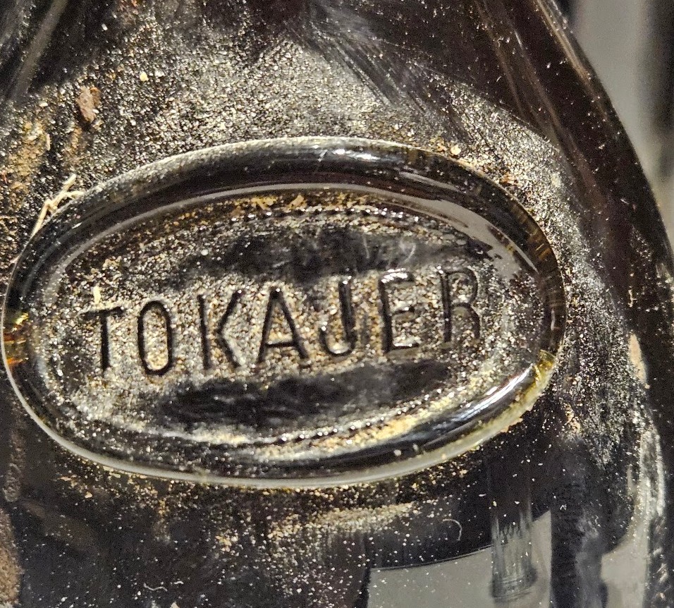 Oval glass seal moulded into dark glass, lettered TOKAUER