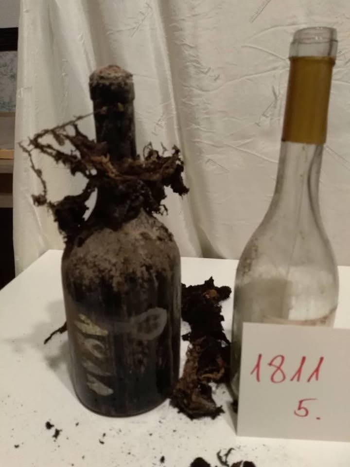 An 1811 bottle beside a modern bottle, the old glass matted with mould growth