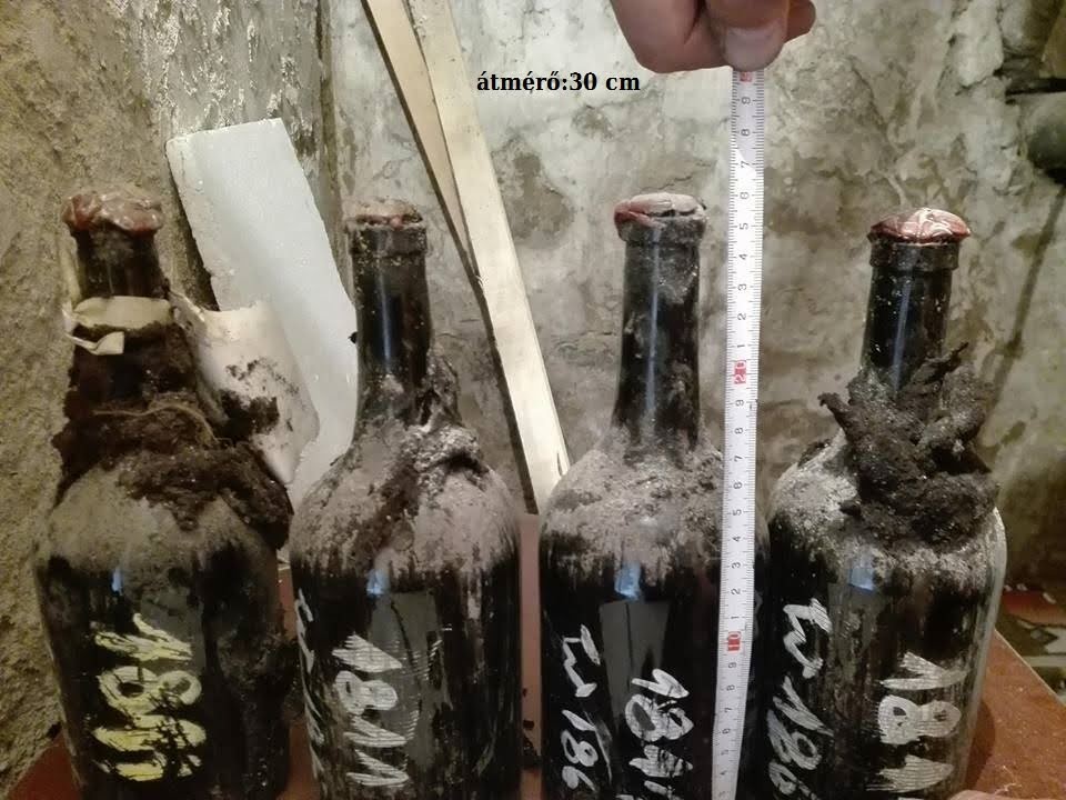 Mould-encrusted paper over a red seal on the shoulder of a black glass bottle