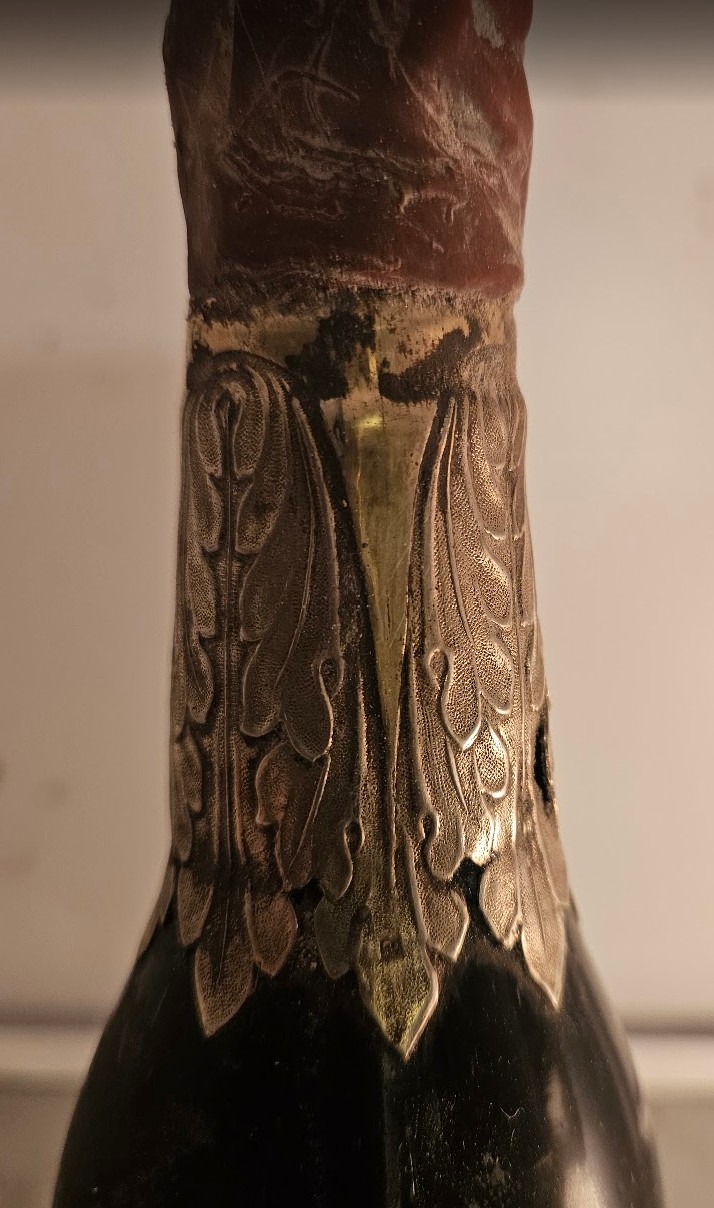 Silver collar with chased acanthus leaves fitted over the neck of a bottle beneath the wax capsule