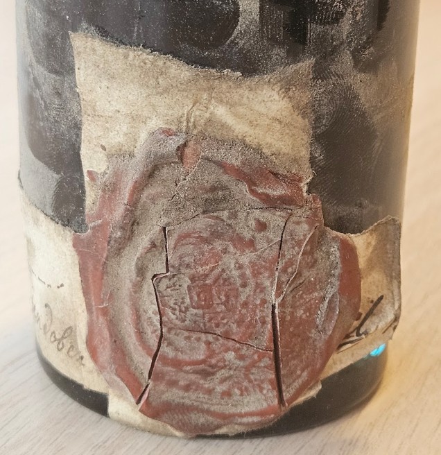 Paper wrapped around the bottle, closed with a large red wax seal