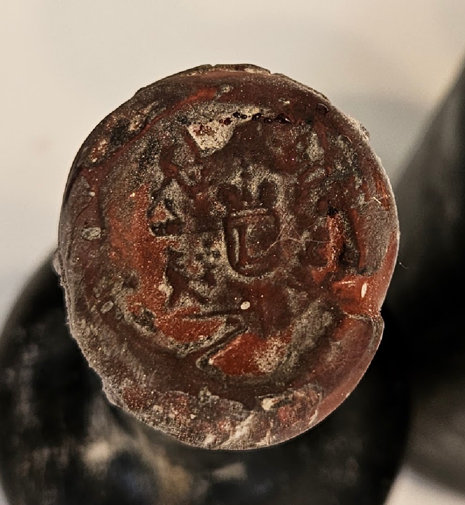 Red wax seal over the cork, impressed with a crowned shield within a lettered border
