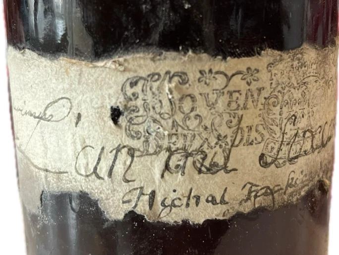 The same label seen wider, the ornamented word MOIEN over the stamp and the handwritten “L’an mil six cen…” running across it