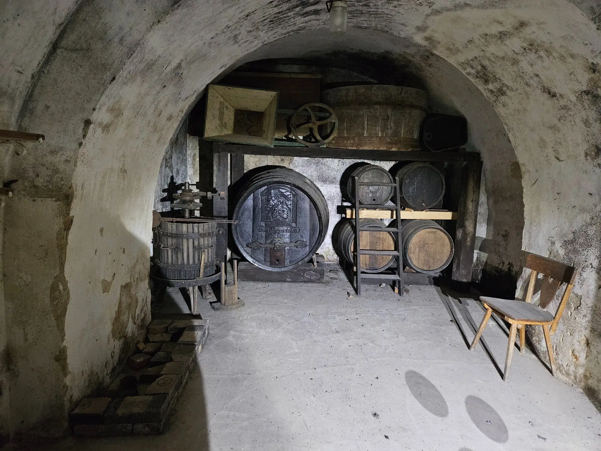 A vaulted cellar with a basket press and carved casks