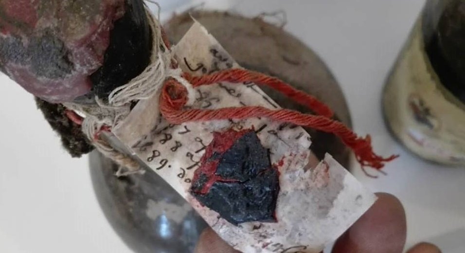 Paper tag on a seventeenth-century bottle, tied with red thread over a wax seal