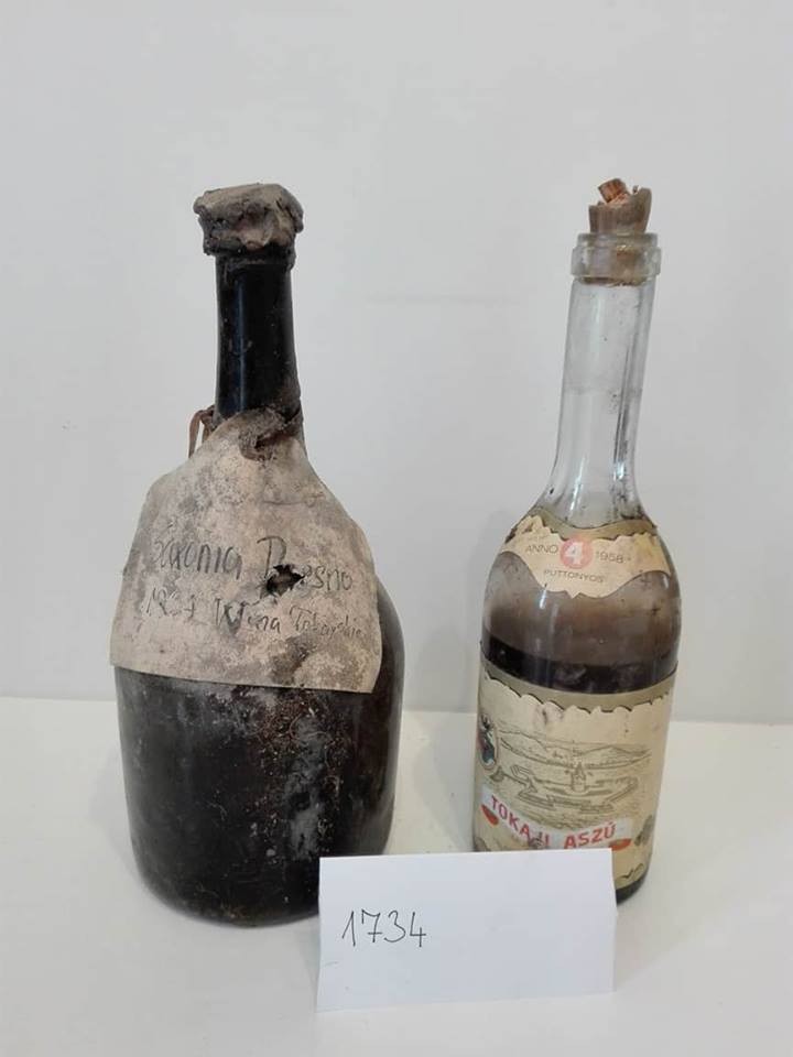 The body of the bottle, cellar deposit over near-black glass, cord at the shoulder