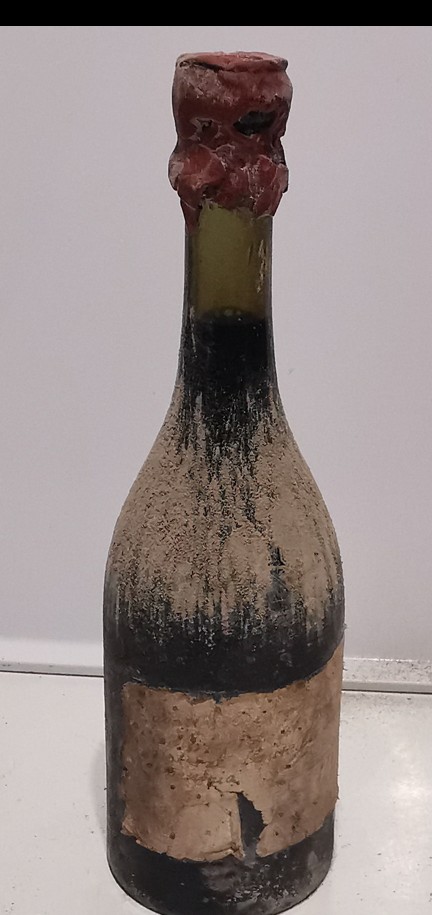 The bottle as found, dust-coated body and red wax capsule