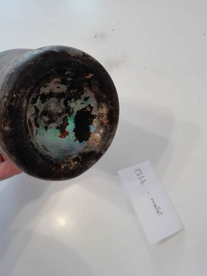 The base of the mallet bottle, showing a deep kick-up and iridescent weathering of the glass