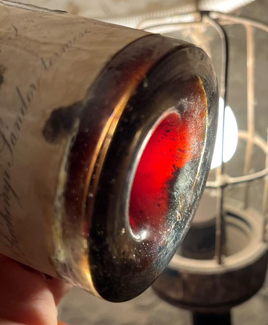 The base of the bottle against a lamp, the wine glowing deep red