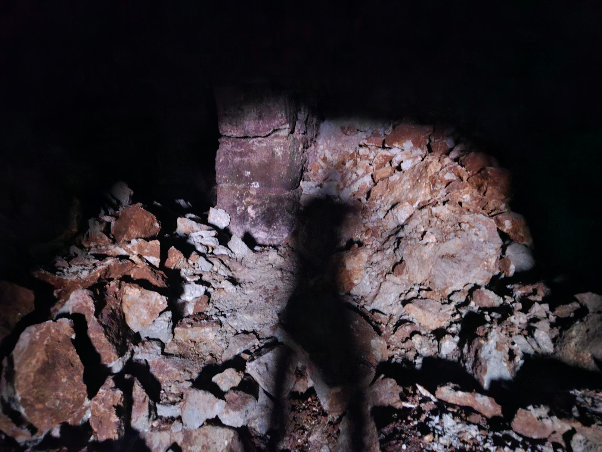 A rubble-filled cellar section lit by torch