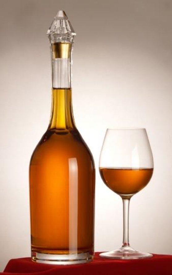 The Dusóczky bottle: a tall clear bottle of amber Tokaji with a faceted glass and gilt closure, beside a filled glass