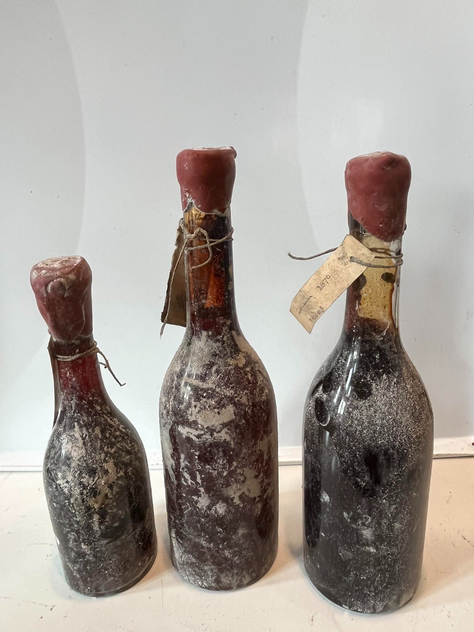 Three old Tokaji bottles with red wax capsules and paper tags