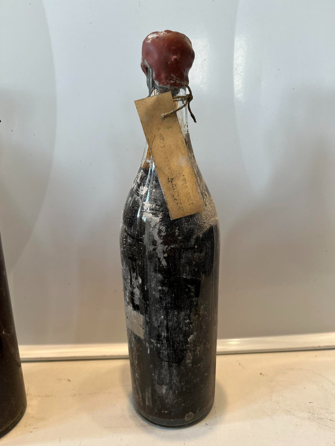 A bottle from the Wilanów cellar, red wax capsule over the cork, a card tag tied to the neck