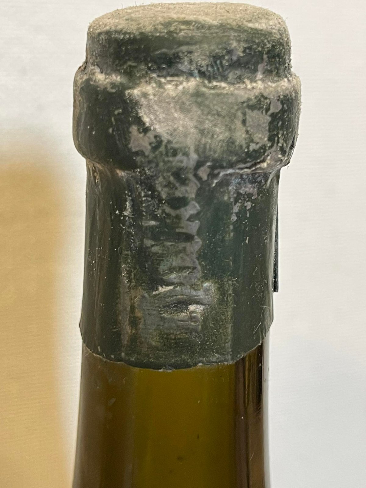 Dark green lacquer capsule, embossed, on a Hofkeller bottle