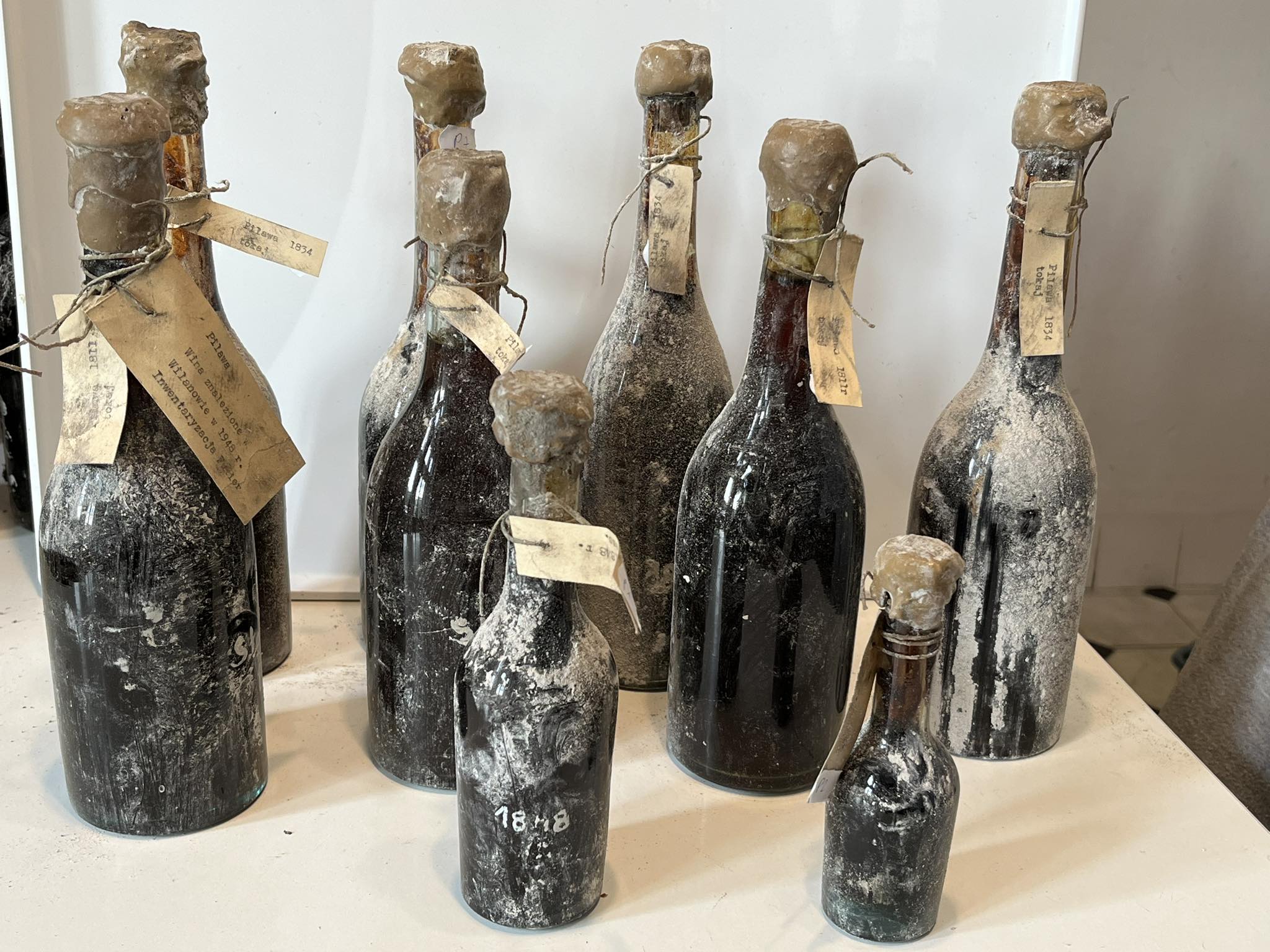 Eight tagged bottles from the Pilawa cellar standing together, labels reading Pilawa 1834 and 1848