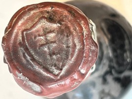 The red wax seal on top of the capsule, a shield impression