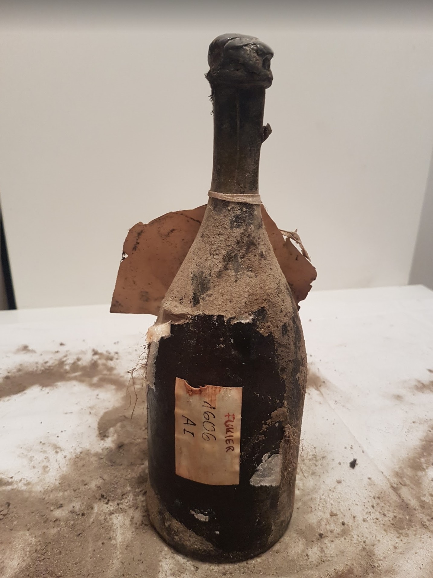 The bottle as found: wrapped shoulder, corded neck, the label reading 1606 FUKIER A I